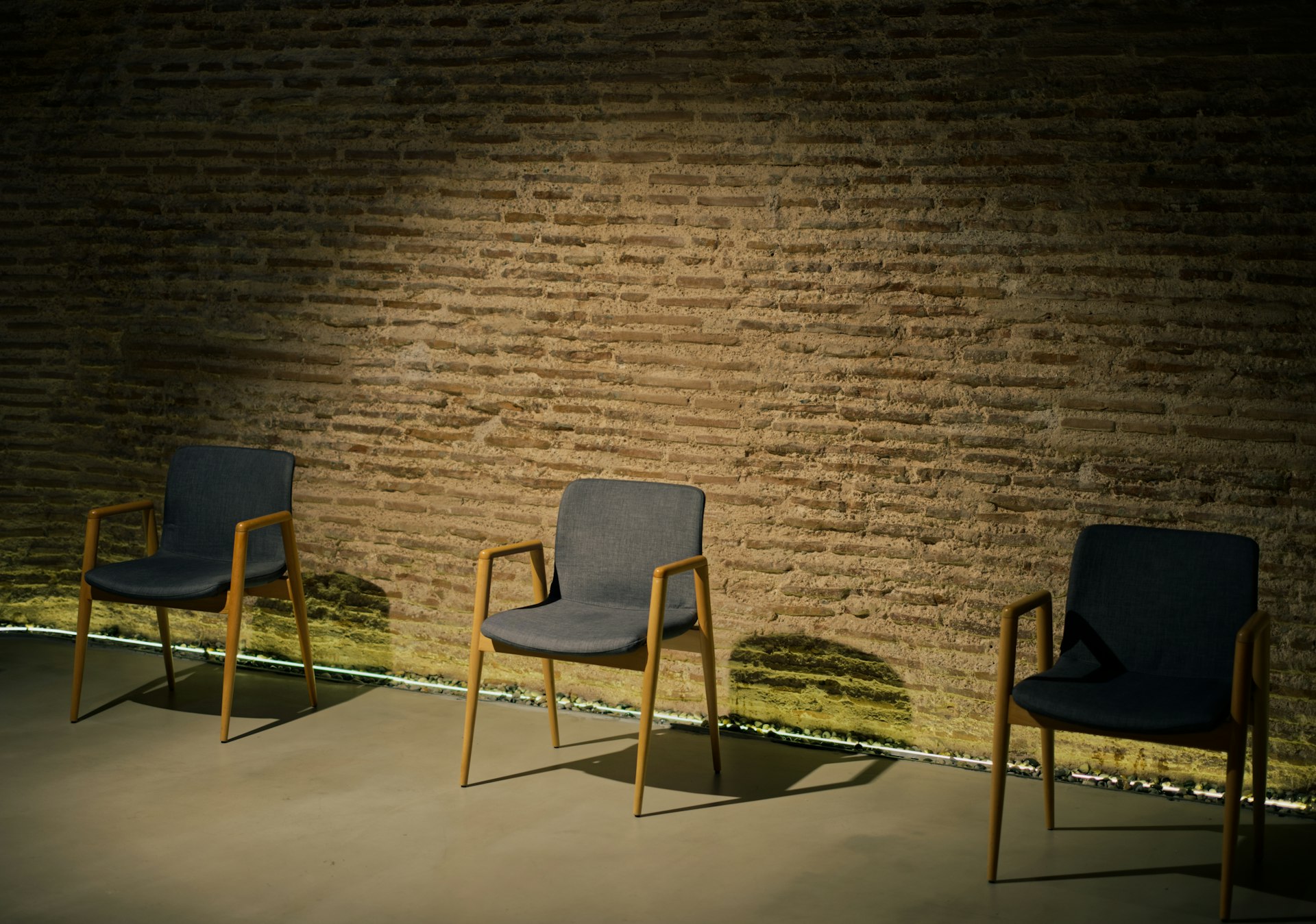 A row of chairs sitting next to a brick wall